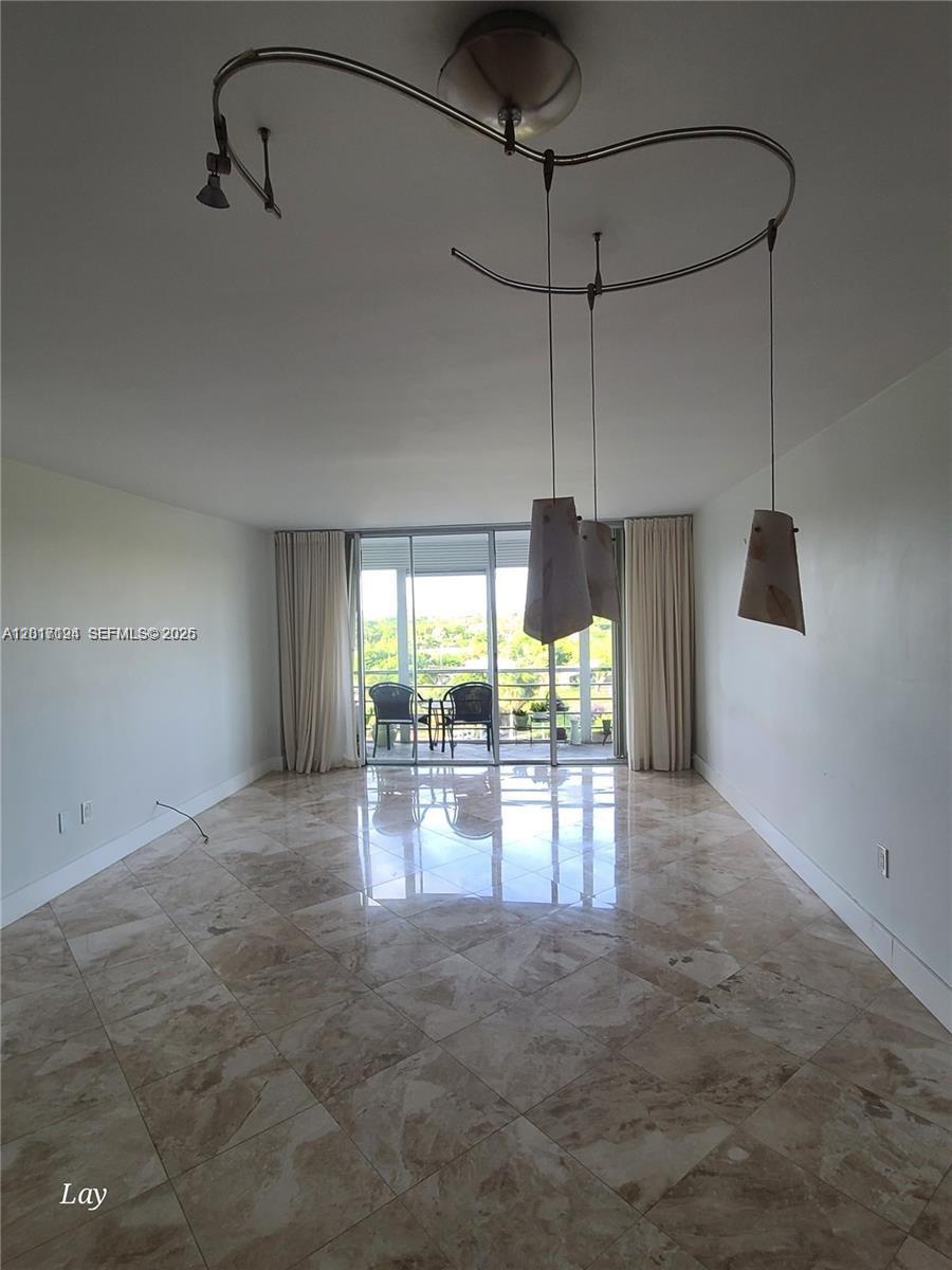 A living room features beige marble tile flooring, white walls, and a modern pendant light fixture — NORTH MIAMI BEACH, FL