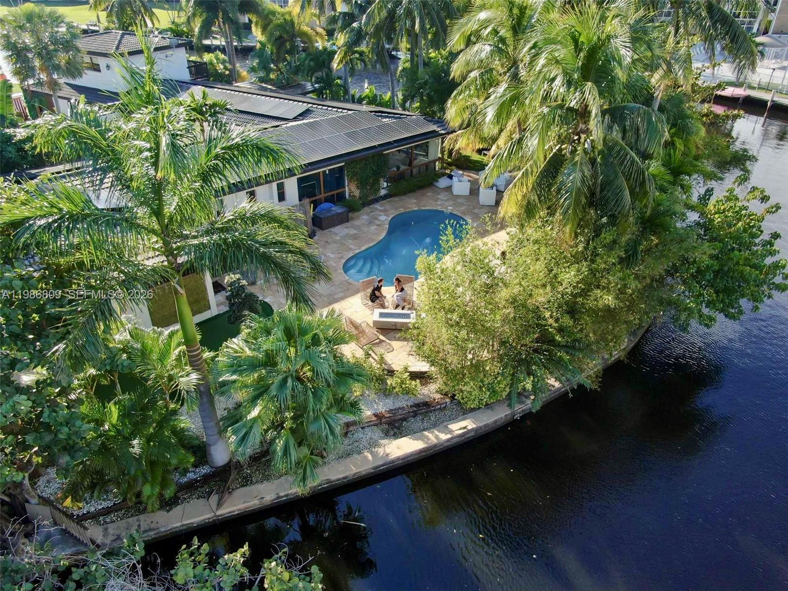 An aerial view of a waterfront home featuring a pool, patio, and lush landscaping — 1675 Coral Gardens Dr, Wilton Manors FL 33334, WILTON MANORS, FL