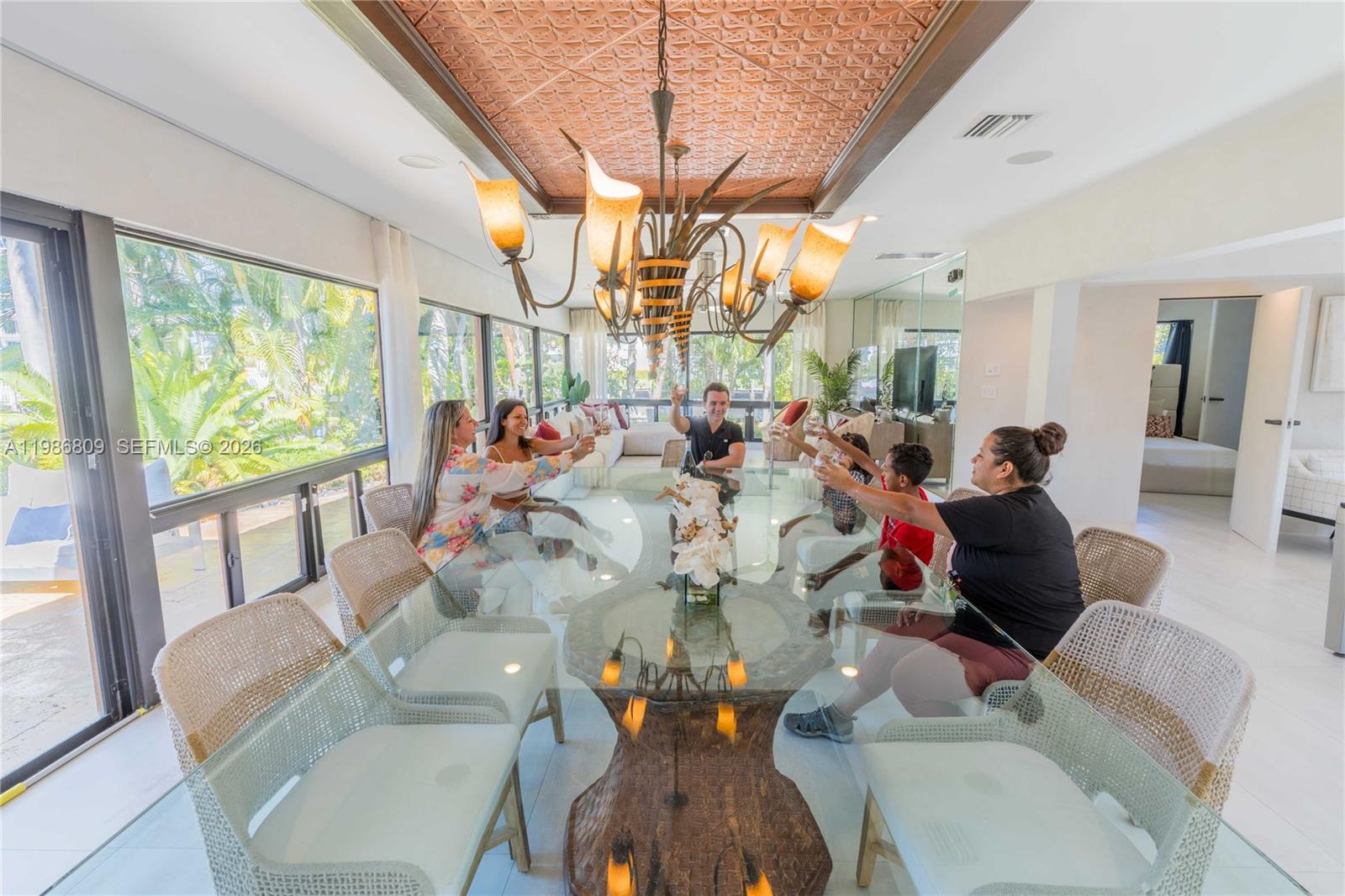 A family toasts at a glass dining table beneath a decorative copper-toned ceiling — 1675 Coral Gardens Dr, Wilton Manors FL 33334, WILTON MANORS, FL
