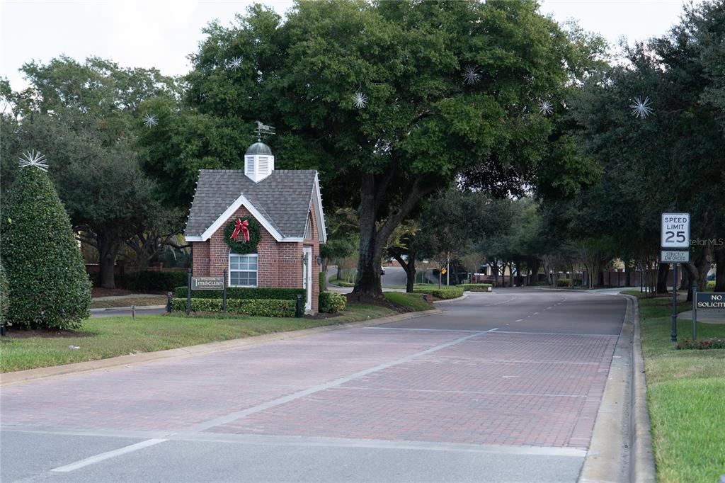 A brick gatehouse stands at the entrance of a residential community with paved roads — 552 TETON STREET, LAKE MARY, FL