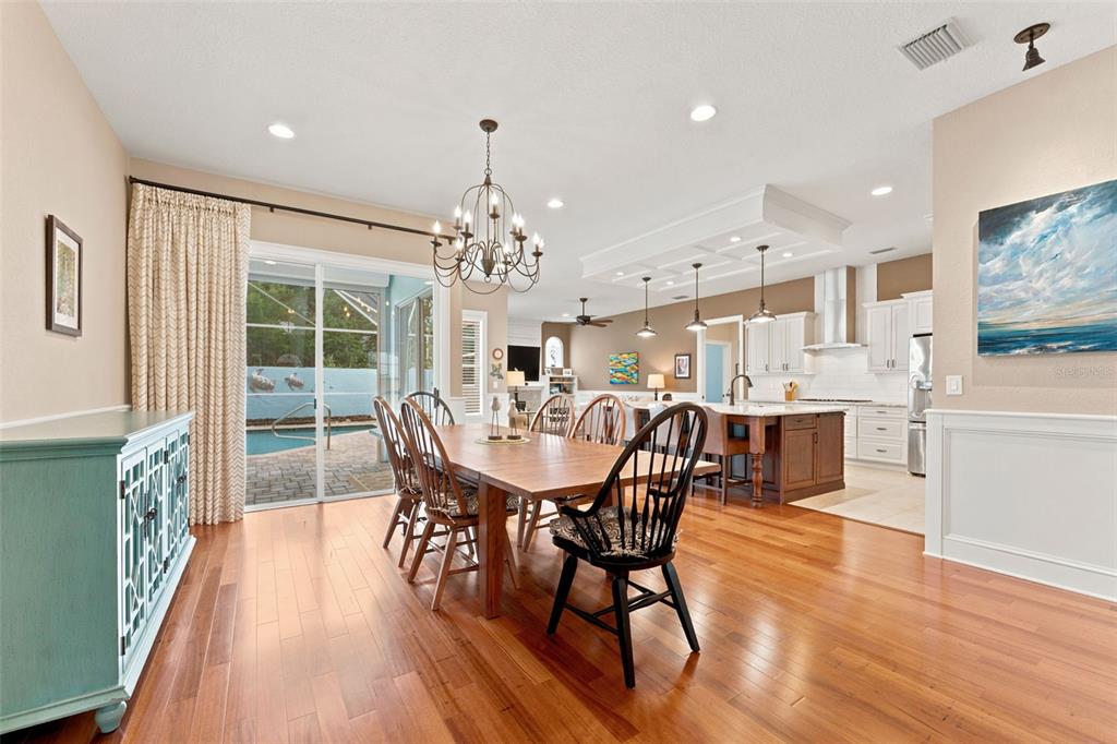 A dining room with a wooden table and chairs sits adjacent to a modern kitchen — 2407 DANA DRIVE, SAFETY HARBOR, FL