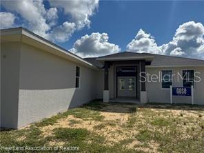 The exterior of a single-story house features a covered entryway and a front yard — 4298 N COURSE LANE, AVON PARK, FL
