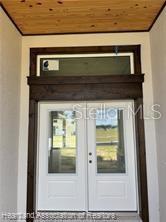 A set of white double doors with glass panels sits beneath a dark wood frame — 4298 N COURSE LANE, AVON PARK, FL
