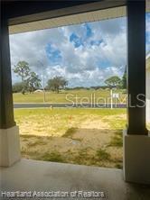 A view from a covered porch looking out over a grassy lot and a road — 4298 N COURSE LANE, AVON PARK, FL