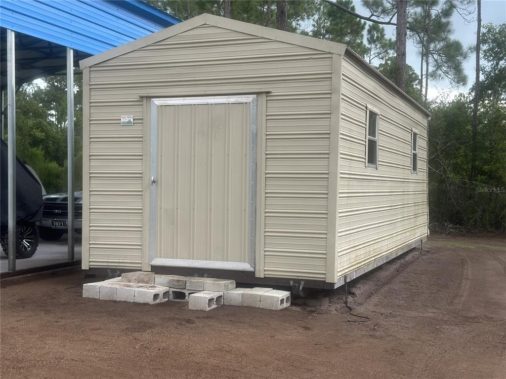 A tan metal storage shed sits on concrete blocks on a dirt lot — 10220 CROTTY AVENUE, HASTINGS, FL
