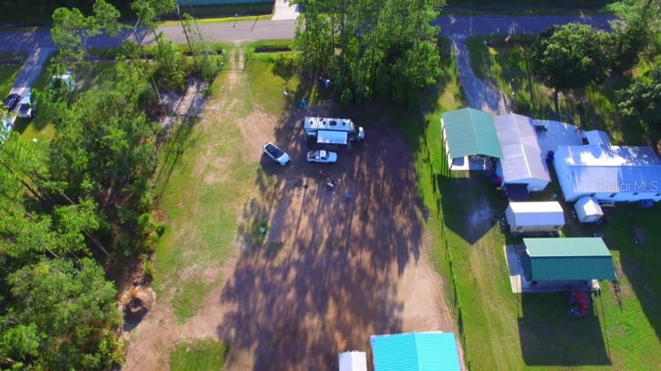 An aerial view shows a large dirt lot with a camper, vehicles, and several outbuildings — 10220 CROTTY AVENUE, HASTINGS, FL