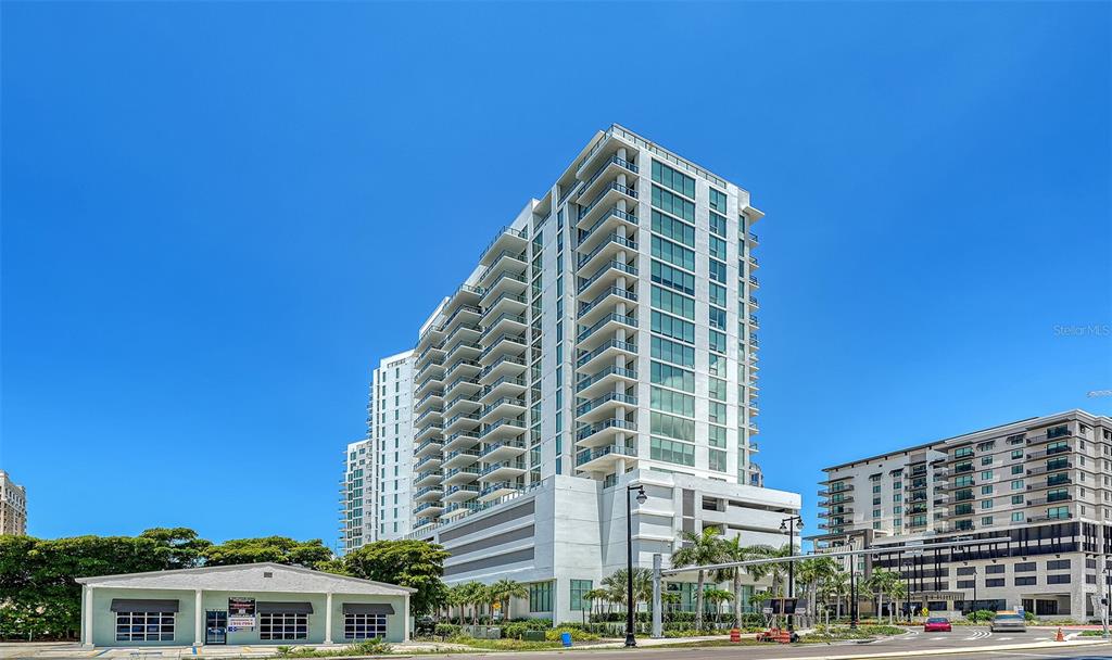 A tall, modern white residential high-rise building stands next to a smaller single-story commercial structure — 301 QUAY UNIT 1507, SARASOTA, FL