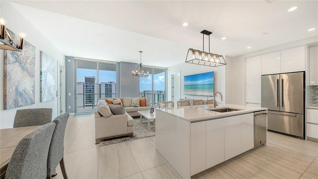 A modern open-concept kitchen and living area with white cabinetry, stainless appliances, and balcony views — 301 QUAY UNIT 1507, SARASOTA, FL