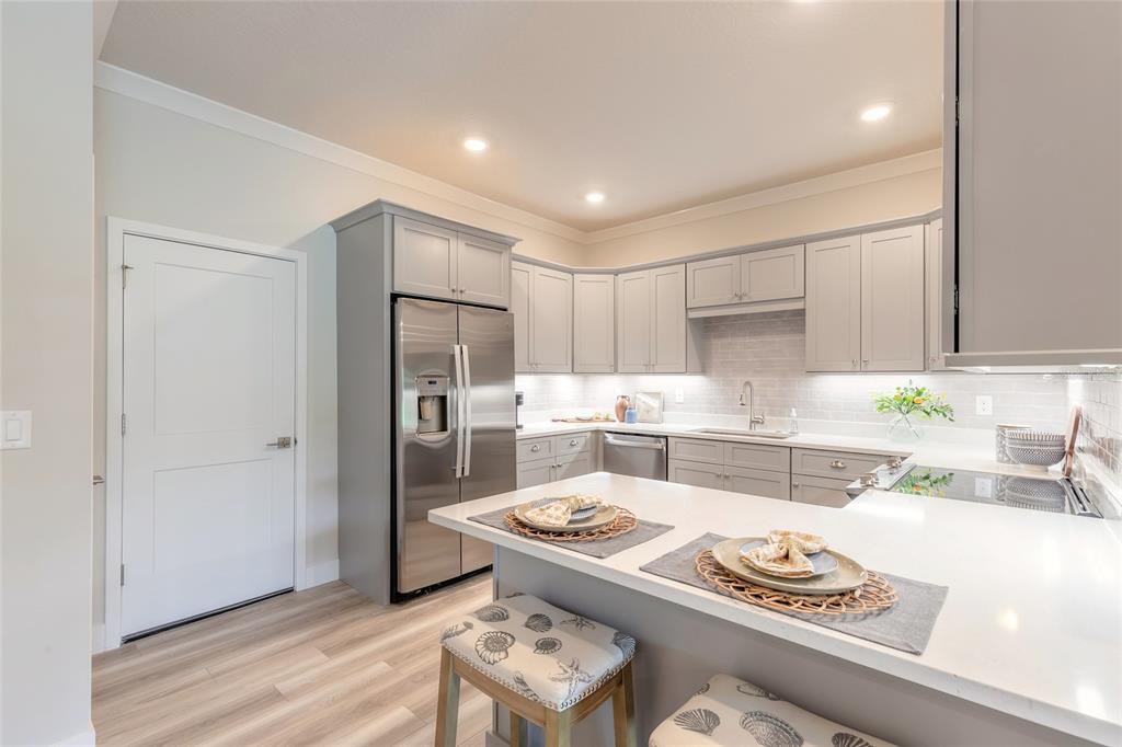 A modern kitchen features gray cabinetry, stainless steel appliances, and a white quartz island countertop — 3065 ISLES WAY, NEW SMYRNA BEACH, FL