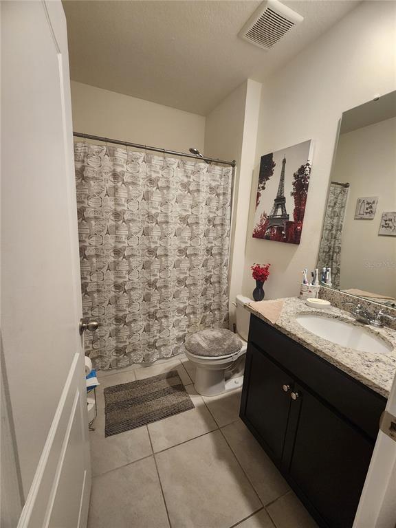 A bathroom features a granite-topped vanity, a toilet, and a shower with a patterned curtain — 1075 GRIFFON AVENUE, LAKE ALFRED, FL