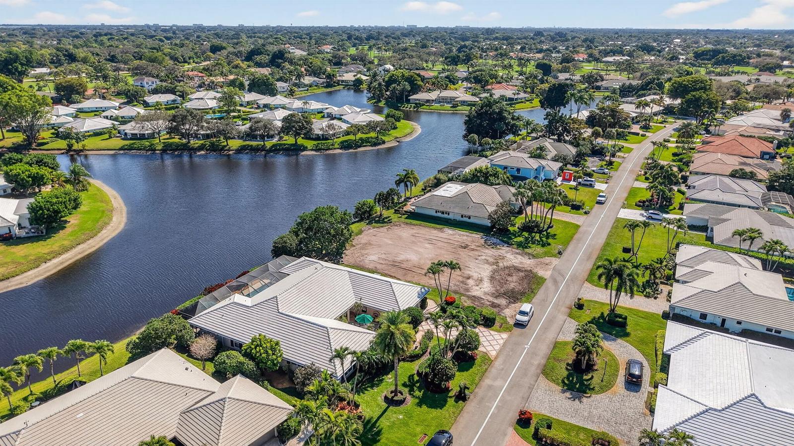 An aerial view shows a residential neighborhood with a vacant lot beside a lake — 11740 N Lake Drive, Boynton Beach FL 33436, BOYNTON BEACH, FL