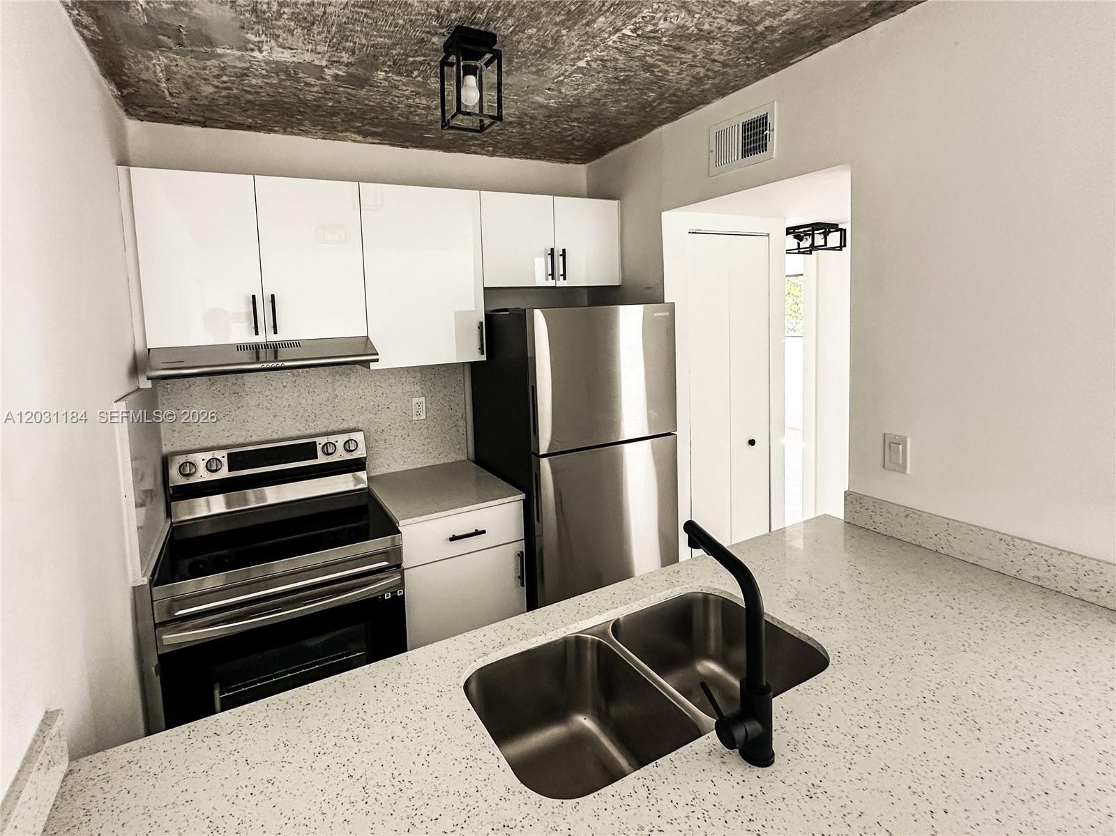 A kitchen features white cabinets, stainless steel appliances, a speckled countertop, and a textured ceiling — 190 NW 69th St # 8, Miami FL 33150, MIAMI, FL