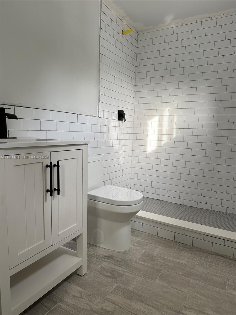 A bathroom features a white vanity, a toilet, and a tiled shower area — 190 NW 69th St # 8, Miami FL 33150, MIAMI, FL