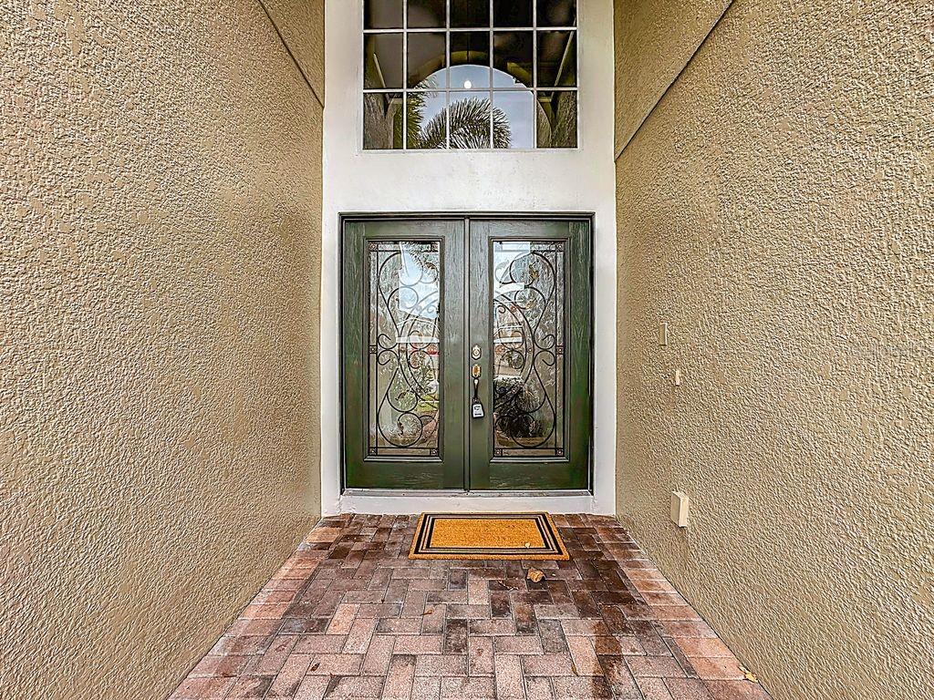 A double front door with decorative glass inserts sits under a large arched transom window — 15612 MONTESINO DRIVE, ORLANDO, FL