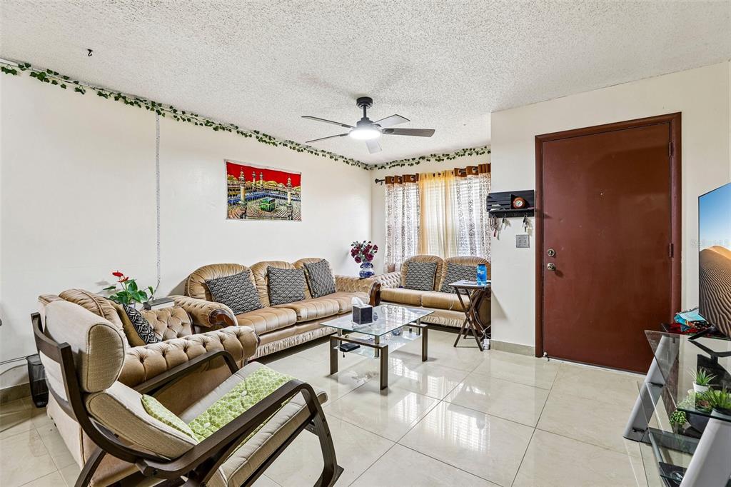 A living room features beige tile floors, a ceiling fan, and multiple tan upholstered sofas — 1320 MILL CREEK PLACE, KISSIMMEE, FL