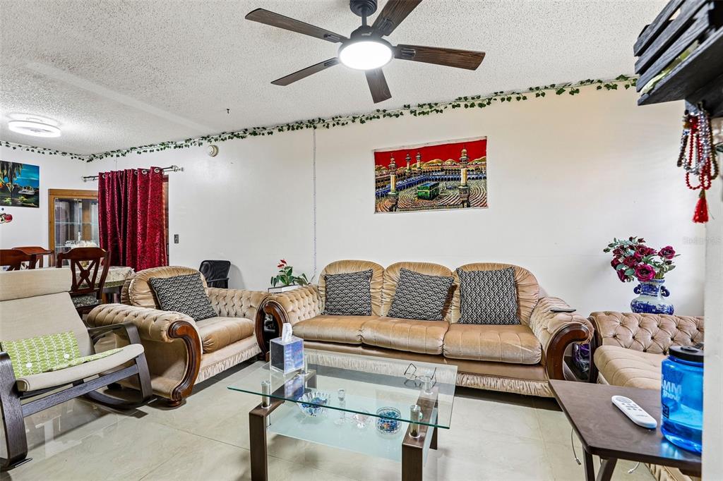 A living room features a tan sofa, a glass coffee table, and a ceiling fan — 1320 MILL CREEK PLACE, KISSIMMEE, FL