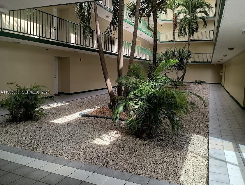 An open-air courtyard features gravel landscaping, palm trees, and multi-level balconies — 8321 NW 7th St # 307, Miami FL 33126, MIAMI, FL