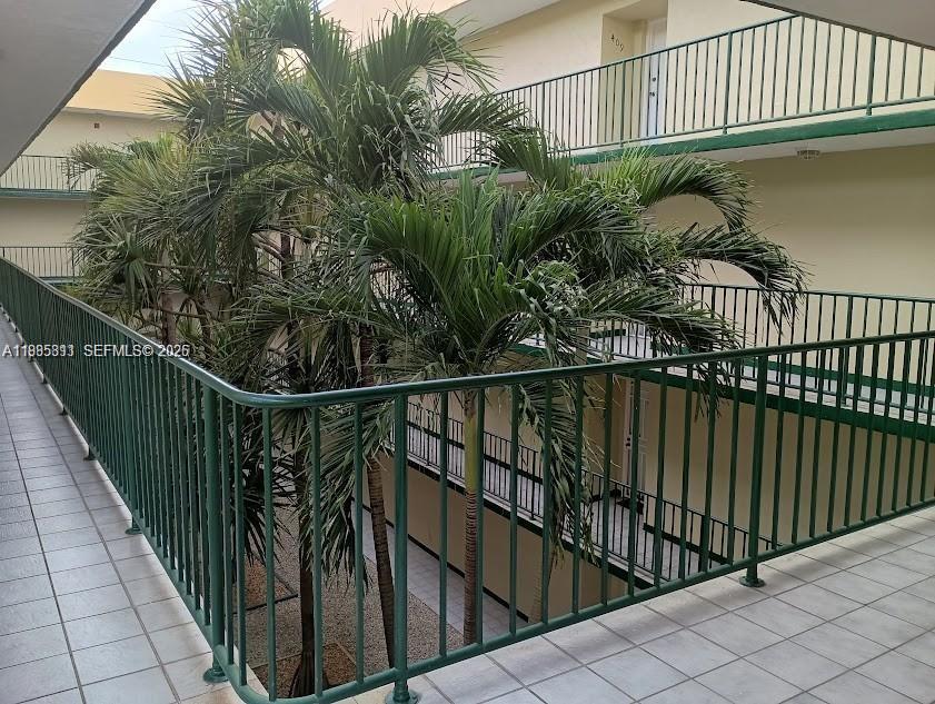 An outdoor walkway with green railings overlooks a courtyard containing several palm trees — 8321 NW 7th St # 307, Miami FL 33126, MIAMI, FL