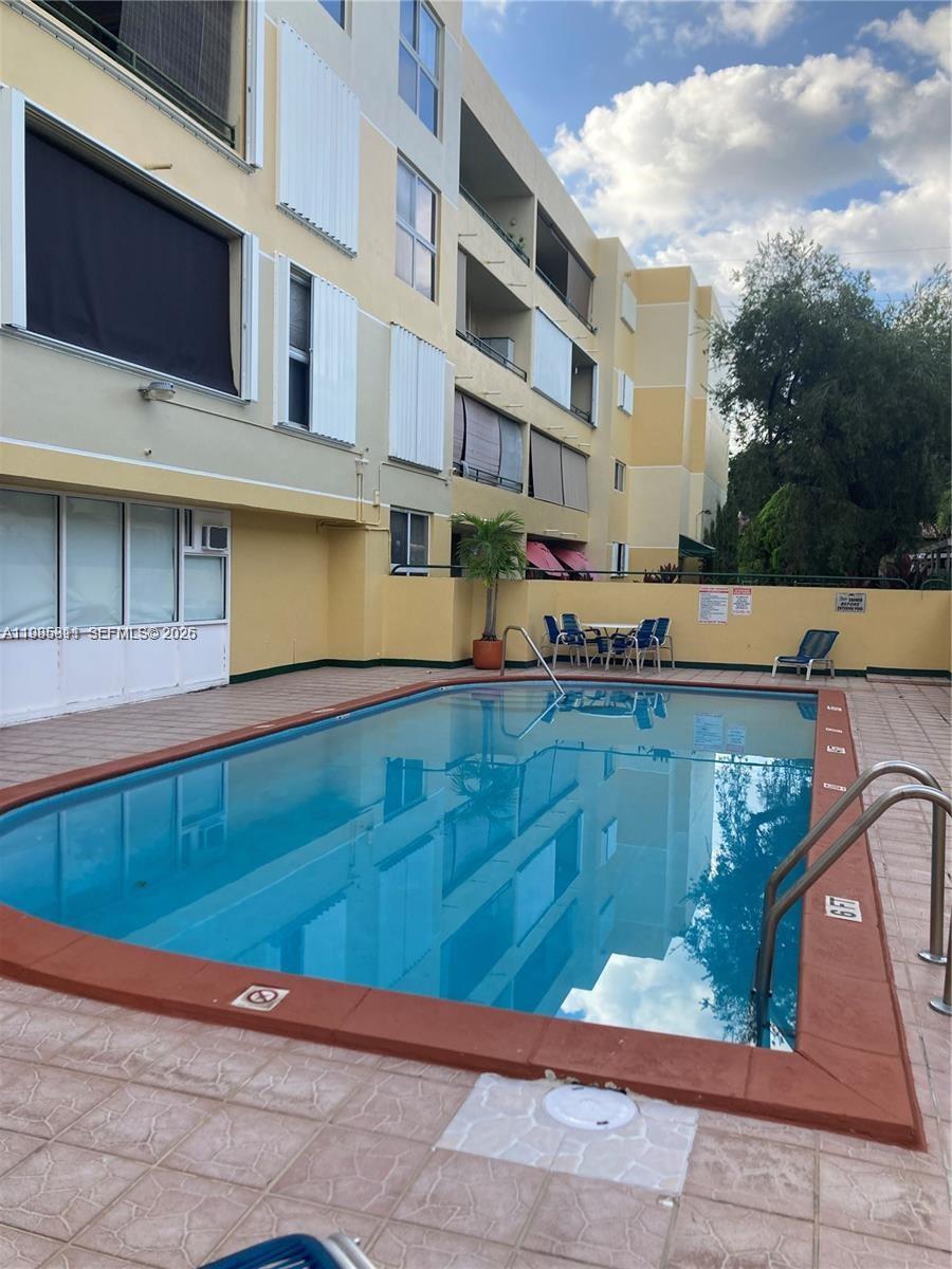 A rectangular swimming pool sits on a tiled patio beside a multi-story apartment building — 8321 NW 7th St # 307, Miami FL 33126, MIAMI, FL