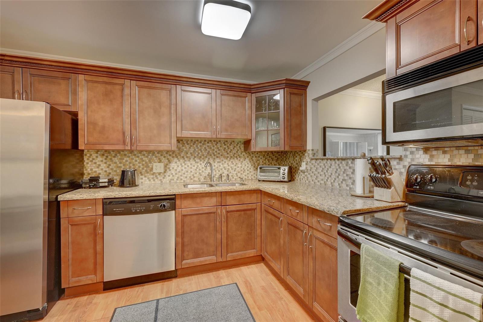 A dining area with a marble-topped table leads into a living room with waterfront views — 823 Cypress Boulevard # 201, Pompano Beach FL 33069, POMPANO BEACH, FL