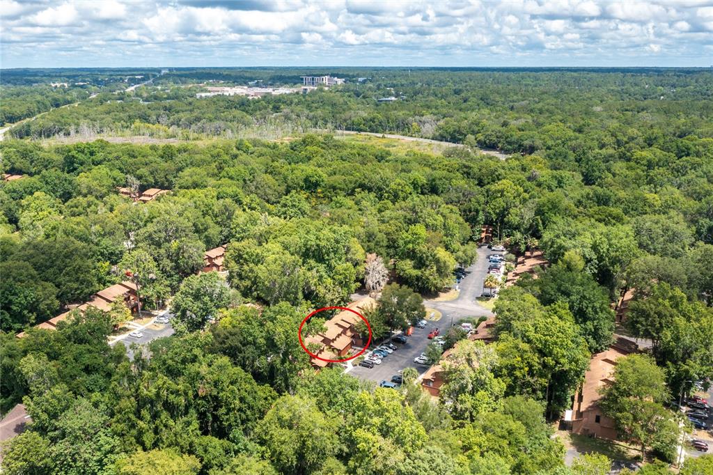 An aerial view shows a multi-unit residential building circled in a wooded complex — 920 SW 55TH TERRACE, GAINESVILLE, FL