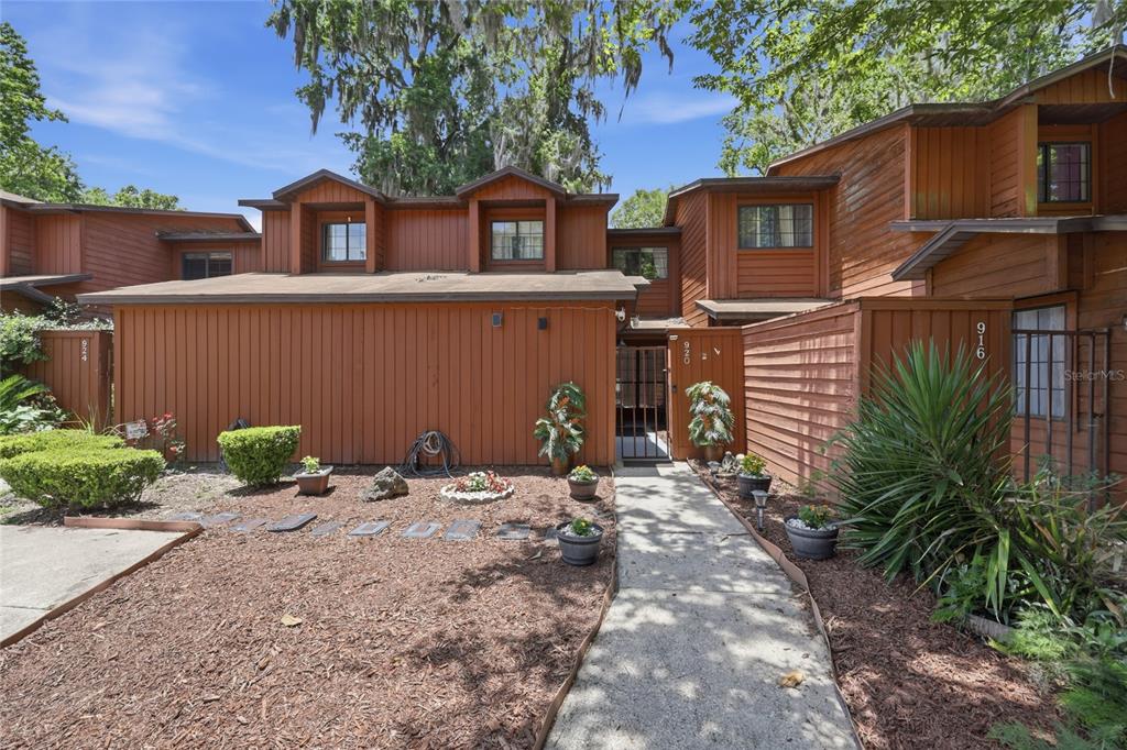 A brown wood-sided multi-unit building with a concrete walkway leading to a gated entrance — 920 SW 55TH TERRACE, GAINESVILLE, FL
