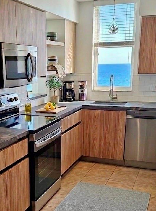 A kitchen features wood-grain cabinets, stainless steel appliances, and a window overlooking the ocean — 770 Claughton Island Dr # 1216, Miami FL 33131, MIAMI, FL