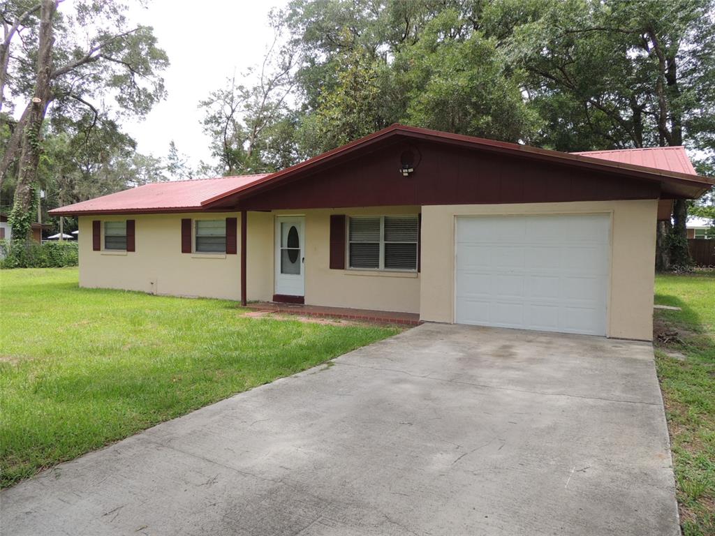 A single-story house with a tan exterior, red metal roof, and an attached one-car garage — 330 SE 6TH STREET, WILLISTON, FL
