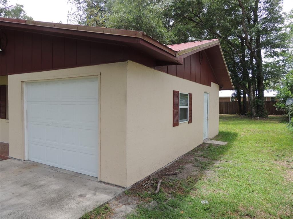 A side view of a house exterior featuring a white garage door and a window — 330 SE 6TH STREET, WILLISTON, FL