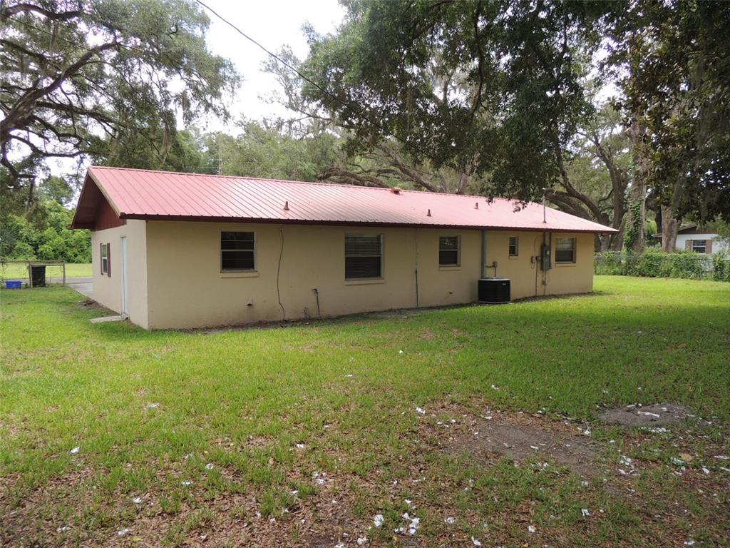 The exterior of a single-story house with a red metal roof and beige stucco walls — 330 SE 6TH STREET, WILLISTON, FL