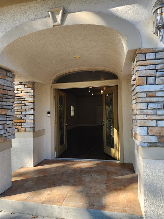 An arched entryway with stone pillars leads to an open doorway revealing a dark interior — 24247 WOLF BRANCH ROAD, SORRENTO, FL