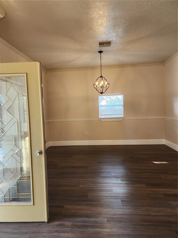 An empty dining room features dark wood-look flooring, beige walls with chair rail molding, and a chandelier — 24247 WOLF BRANCH ROAD, SORRENTO, FL