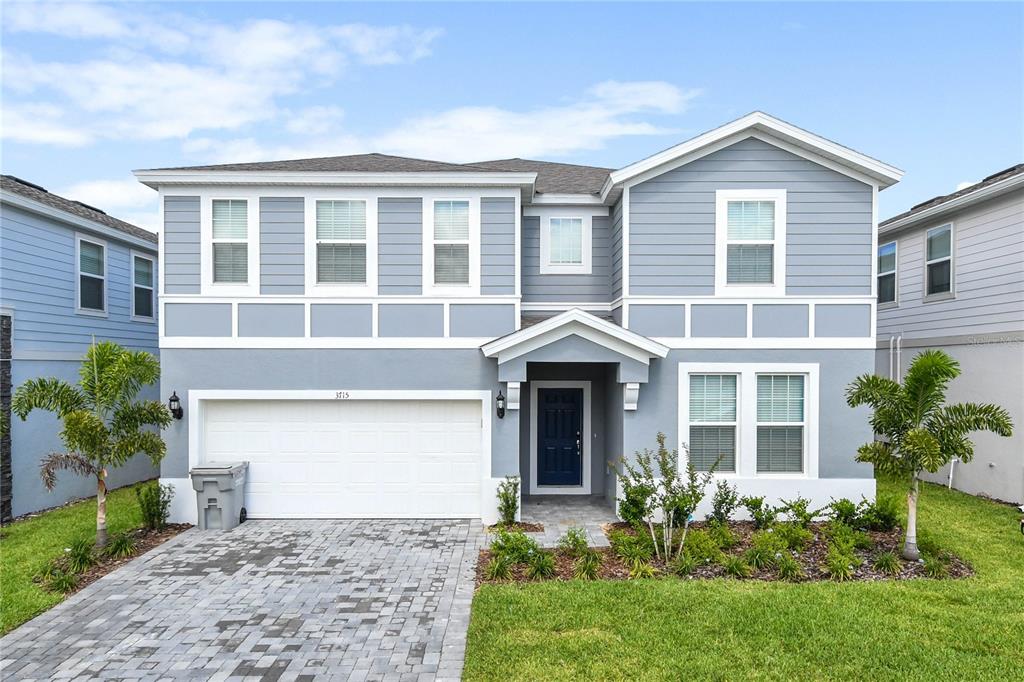 A two-story house with light blue siding, a white garage door, and a paved driveway — 3715 LANA AVENUE, DAVENPORT, FL