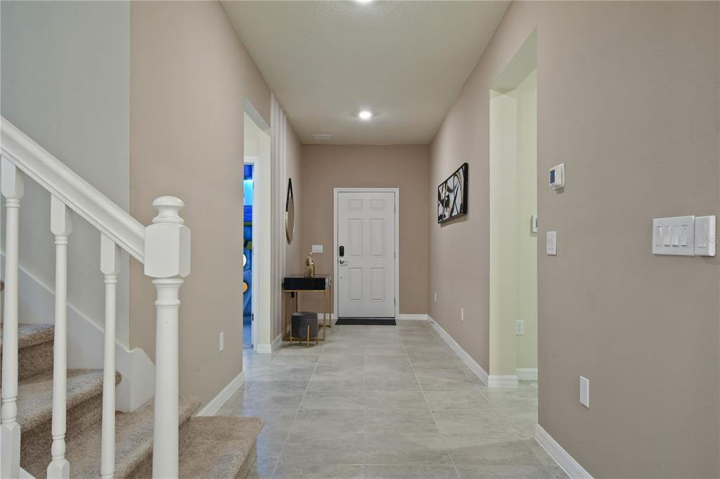 A tiled entryway features a staircase with a white railing and a front door — 3715 LANA AVENUE, DAVENPORT, FL