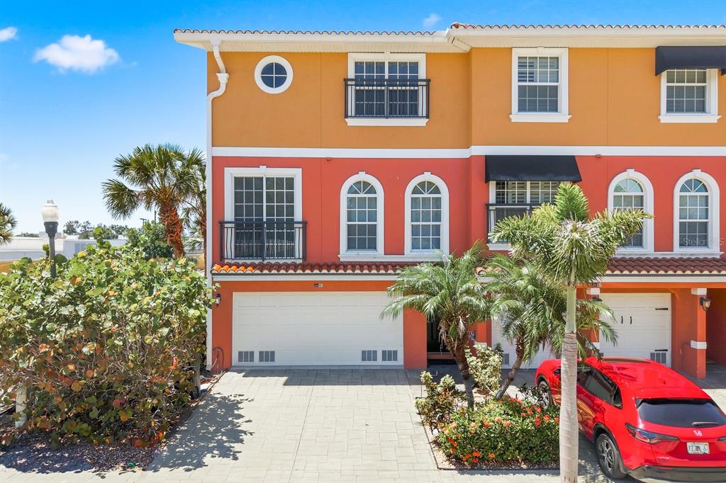 A three-story townhouse with a red and orange exterior, a two-car garage, and palm trees — 47 W MORGAN STREET, TARPON SPRINGS, FL