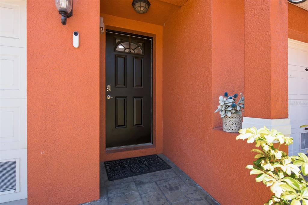 A black front door is set into an orange stucco exterior wall with a porch — 47 W MORGAN STREET, TARPON SPRINGS, FL