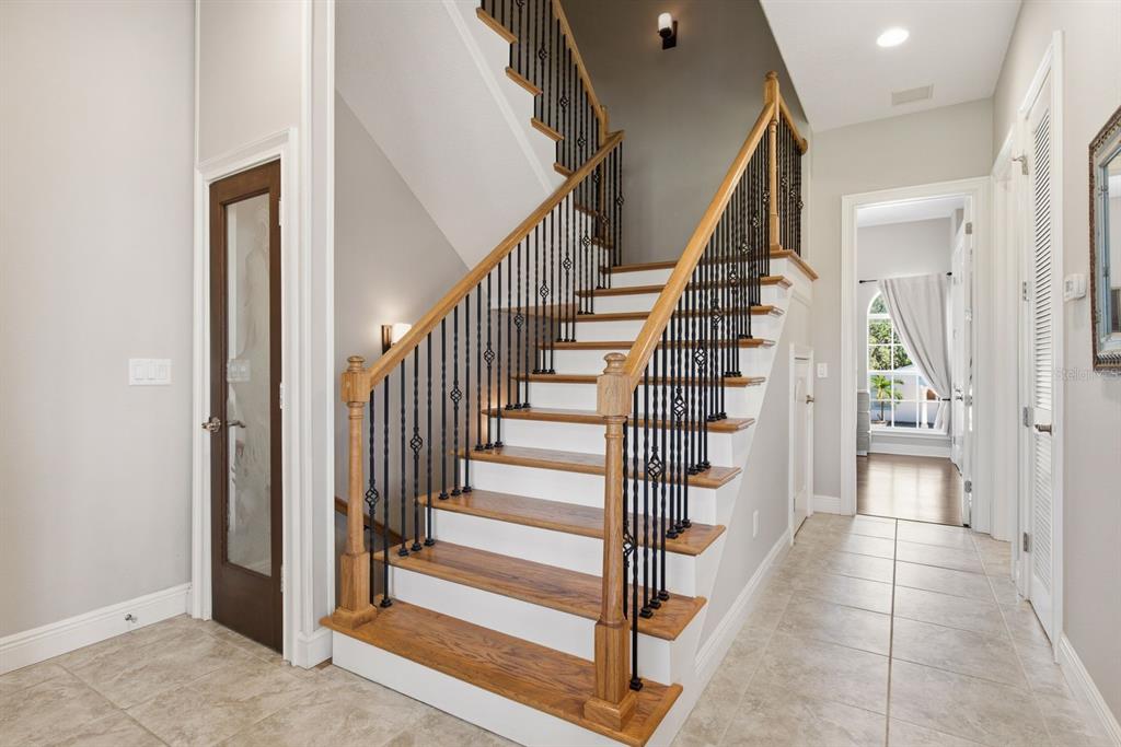 A staircase with wooden treads and black iron railings sits in a tiled entryway — 47 W MORGAN STREET, TARPON SPRINGS, FL