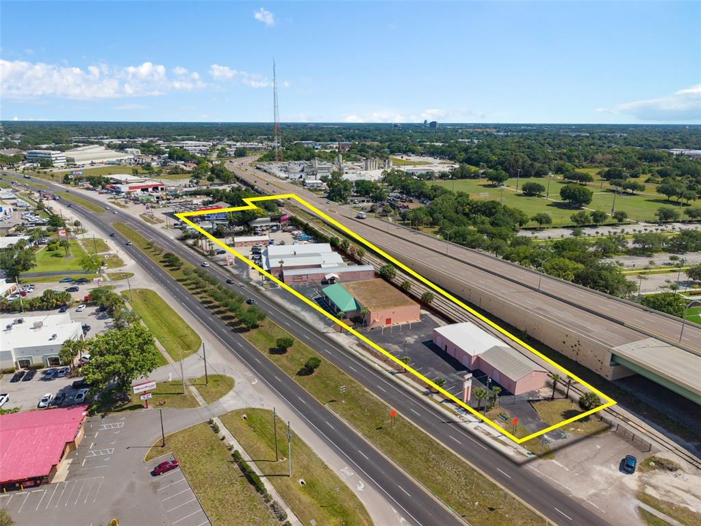 An aerial view shows a commercial property outlined in yellow situated between a road and highway — 4809 N ORANGE BLOSSOM TRAIL, ORLANDO, FL