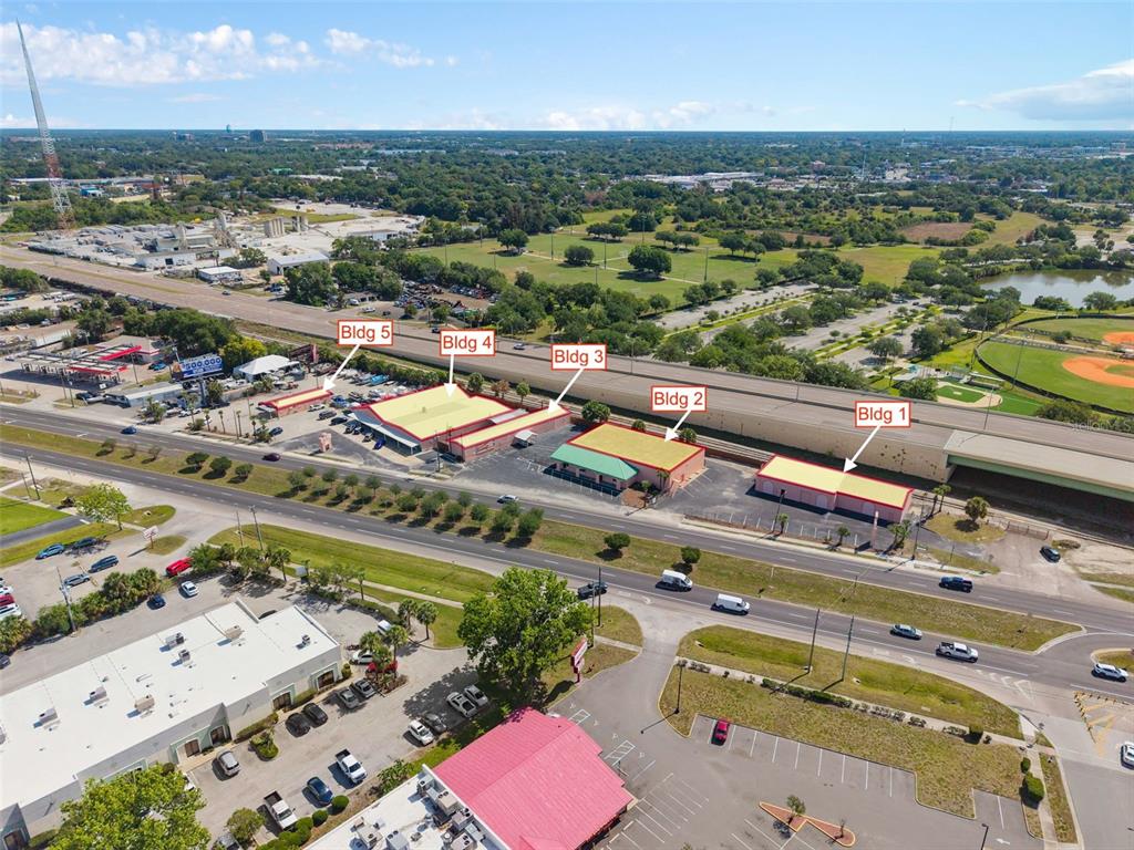An aerial view shows five commercial buildings situated along a road next to a highway — 4809 N ORANGE BLOSSOM TRAIL, ORLANDO, FL