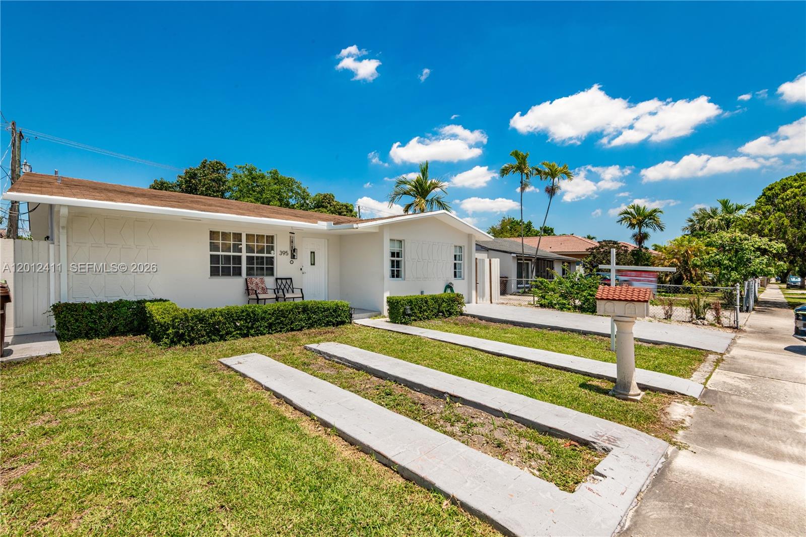 A white single-story house features a front lawn with concrete driveway strips and a mailbox — 395 W 39th Pl, Hialeah FL 33012, HIALEAH, FL