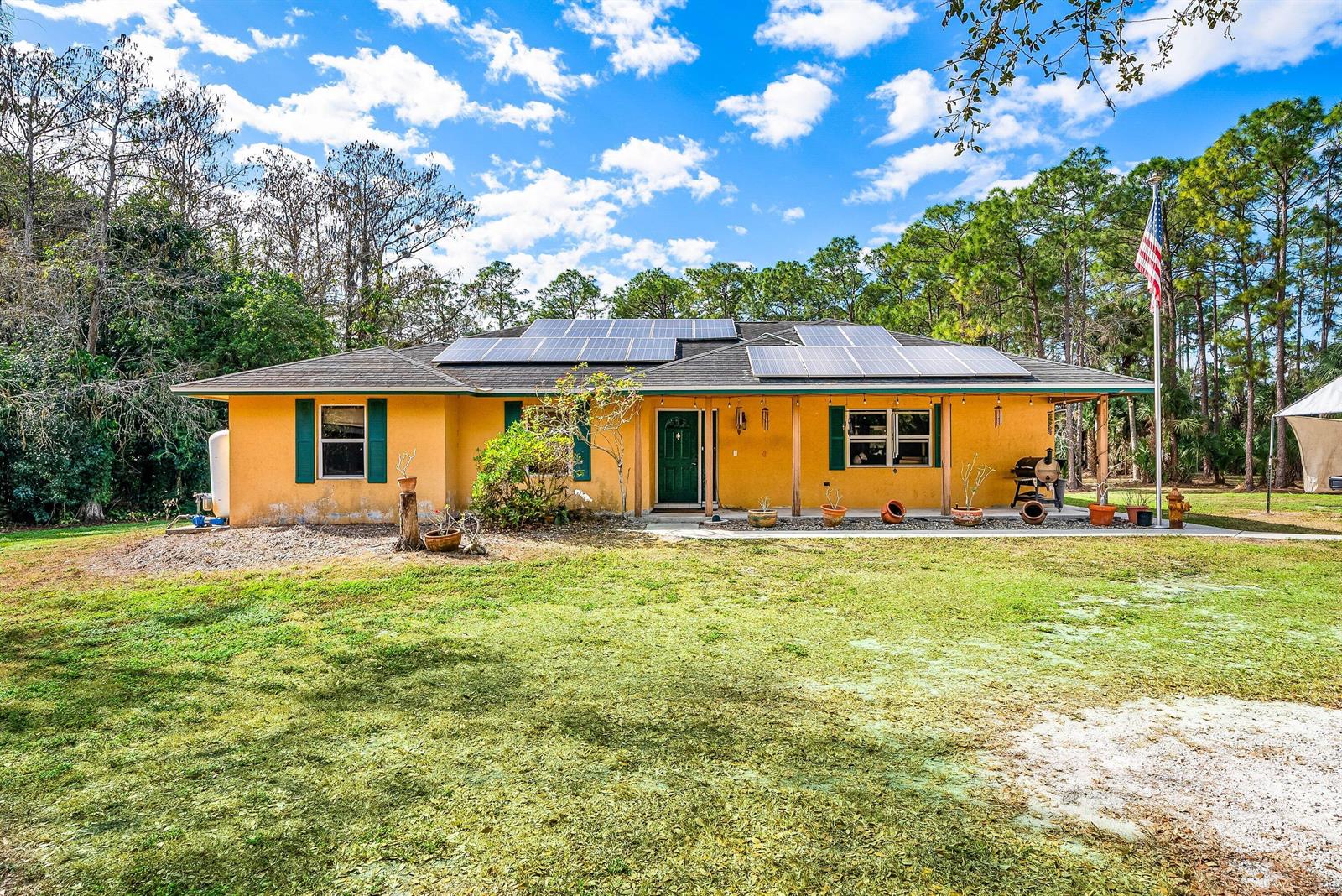 A single-story yellow house with solar panels on the roof and a covered front porch — 2195 F Road, FL 33470, FL