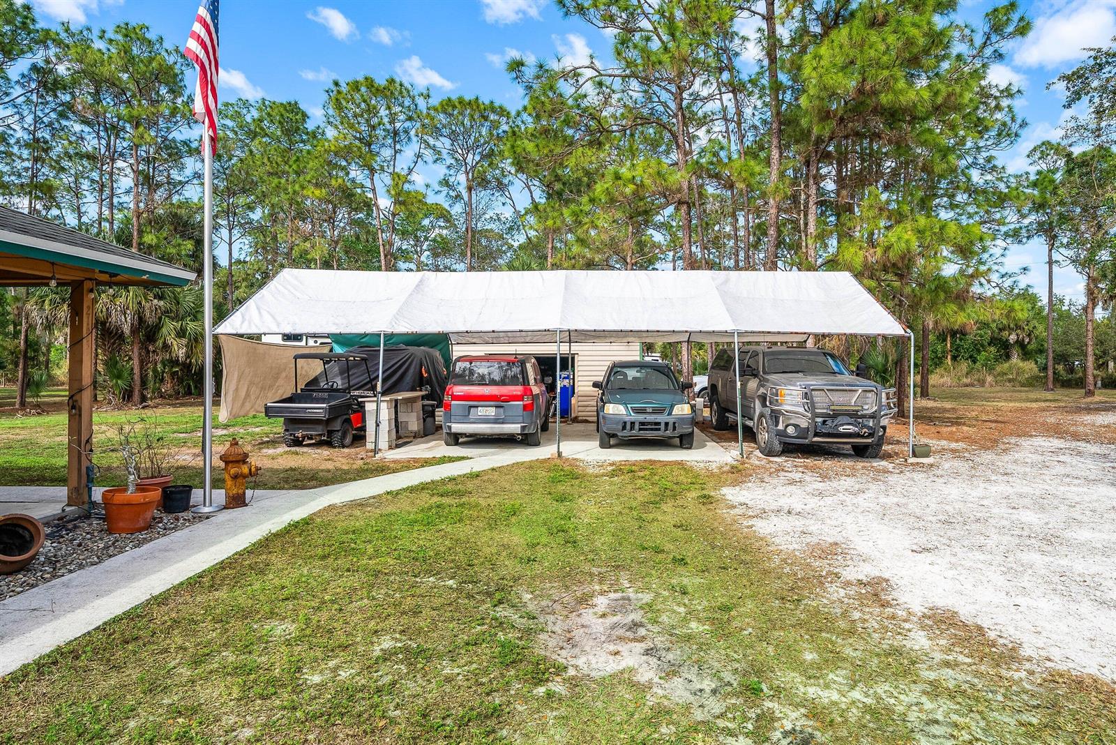 A large white canopy covers a driveway with a golf cart and three parked vehicles — 2195 F Road, FL 33470, FL