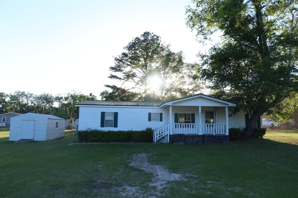 A white single-wide mobile home with a covered front porch and a detached metal shed — 262 SW LYNNWOOD AVENUE, LAKE CITY, FL