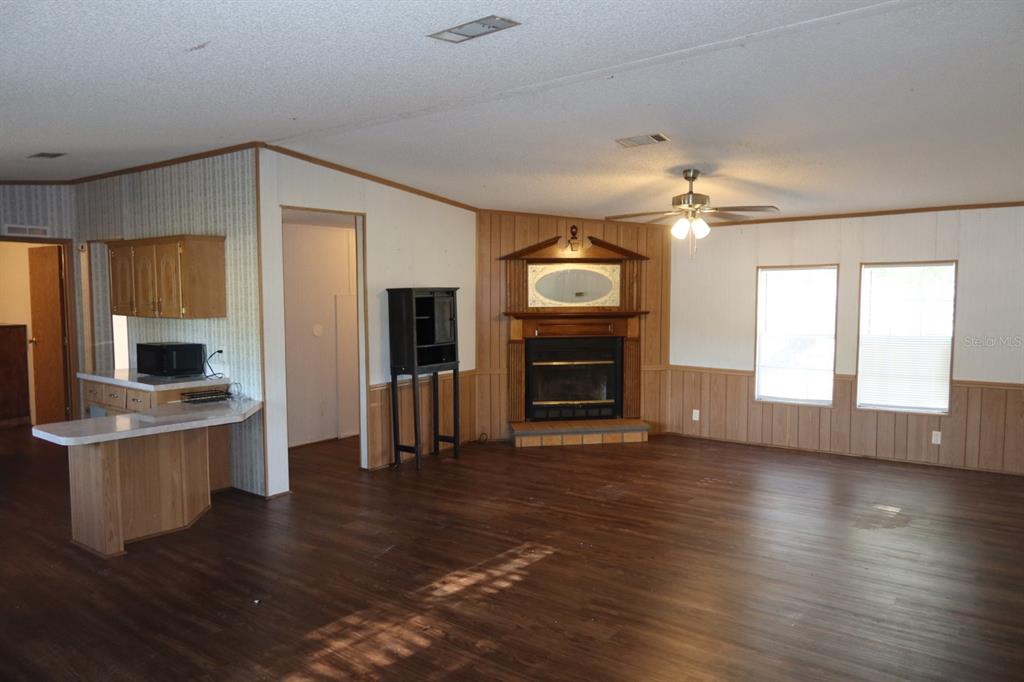 A living room with wood-look flooring, a corner fireplace, and an adjacent kitchen counter — 262 SW LYNNWOOD AVENUE, LAKE CITY, FL