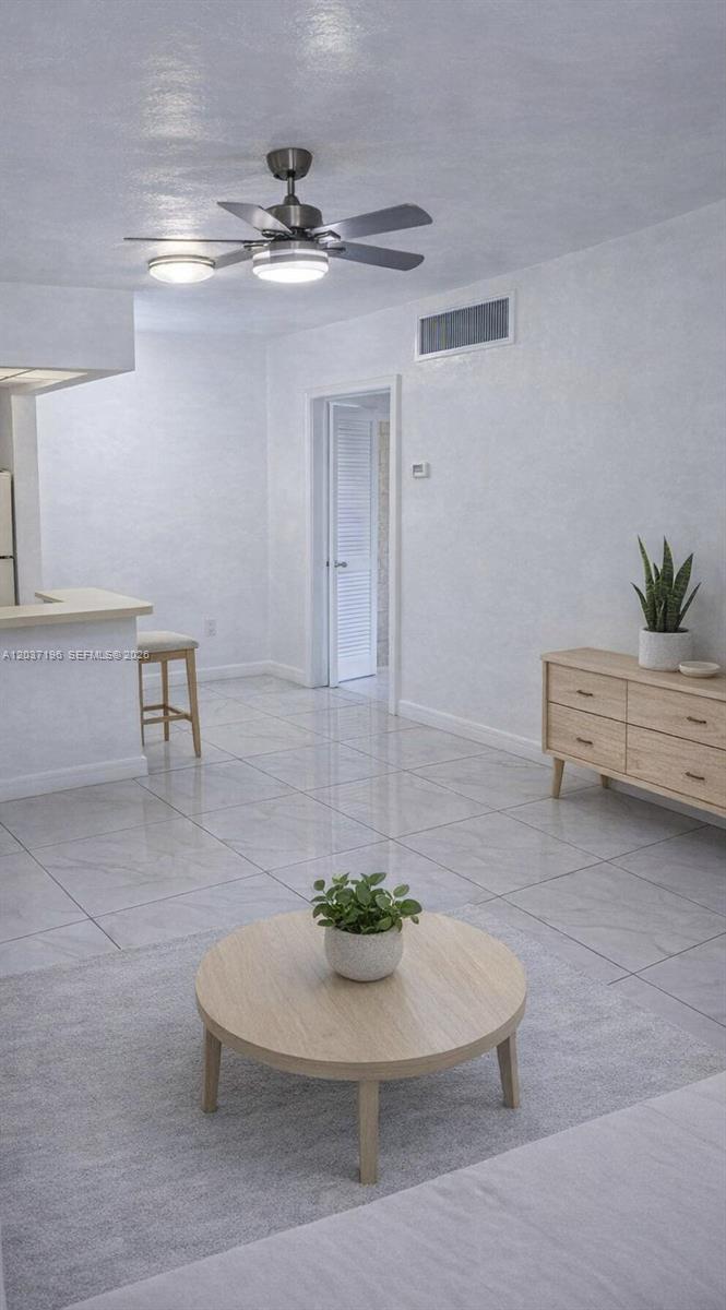 A living room features light tile floors, a ceiling fan, and a wooden coffee table — 7505 SW 82nd St # 322, Miami FL 33143, MIAMI, FL