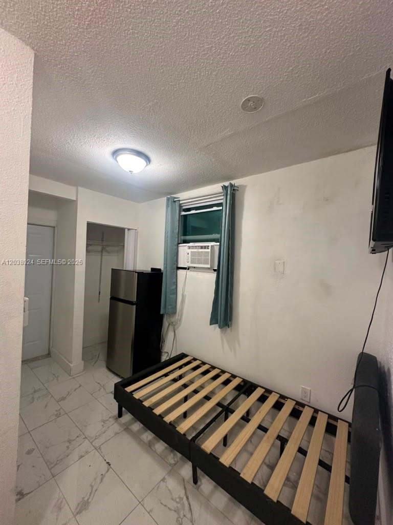 A small bedroom features a bed frame, a refrigerator, and a window air conditioning unit — 655 NW 2nd St # A, Florida City FL 33034, FLORIDA CITY, FL