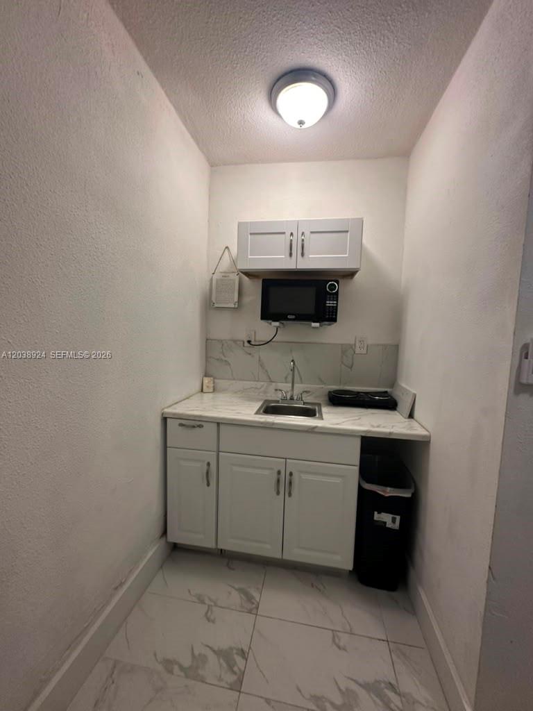 A small kitchenette features white cabinets, a sink, a microwave, and marble-patterned countertops — 655 NW 2nd St # A, Florida City FL 33034, FLORIDA CITY, FL