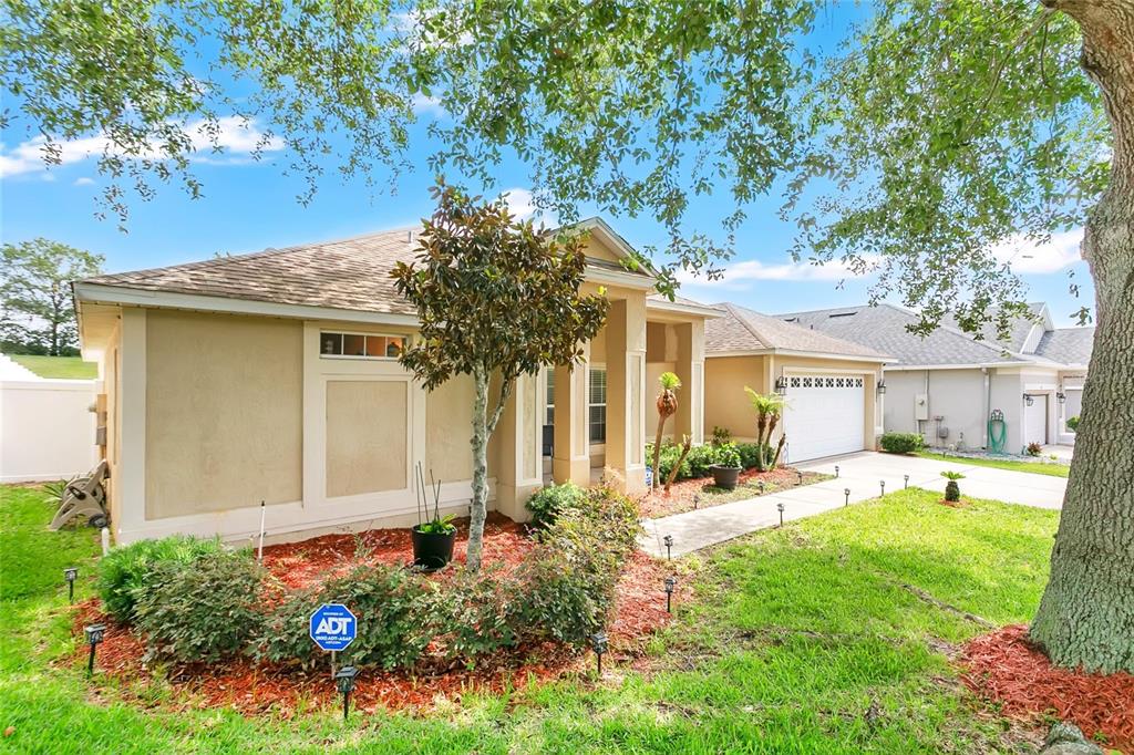 A single-story house with a beige stucco exterior, a two-car garage, and a landscaped front yard — 159 COMPASS ROSE DRIVE, GROVELAND, FL