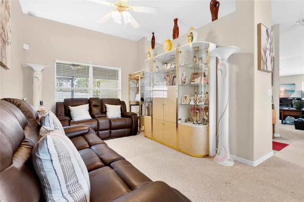 A living room features brown leather sofas, a glass display cabinet, and a ceiling fan — 159 COMPASS ROSE DRIVE, GROVELAND, FL
