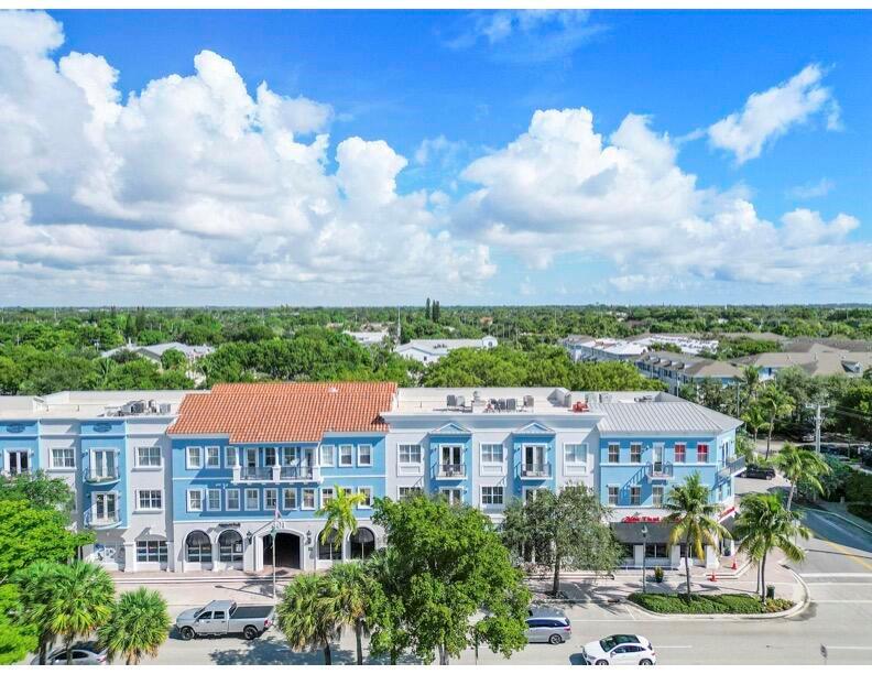 An aerial view of a blue multi-story commercial and residential building with palm trees — 401 W Atlantic Avenue # O13, Delray Beach FL 33444, DELRAY BEACH, FL